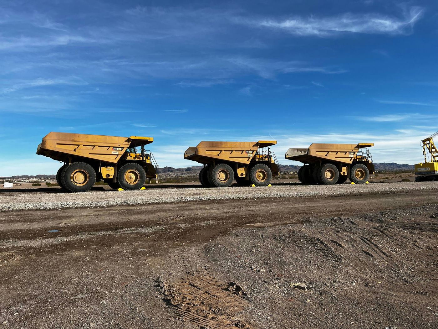 Tres camiones mineros fuera de ruta en fila sobre una explanada