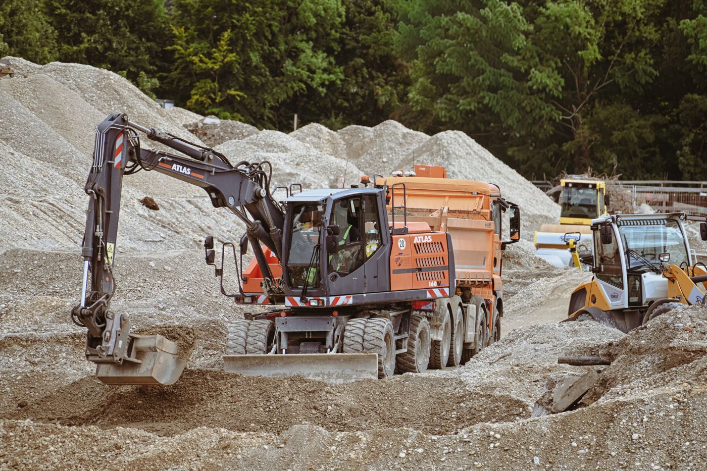 Excavadora sobre ruedas cargando un camión volcador en una obra